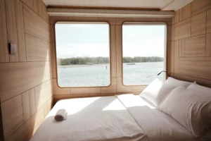 Double bed and sea-view windows in the Lamalera private cabin aboard Mosalaki