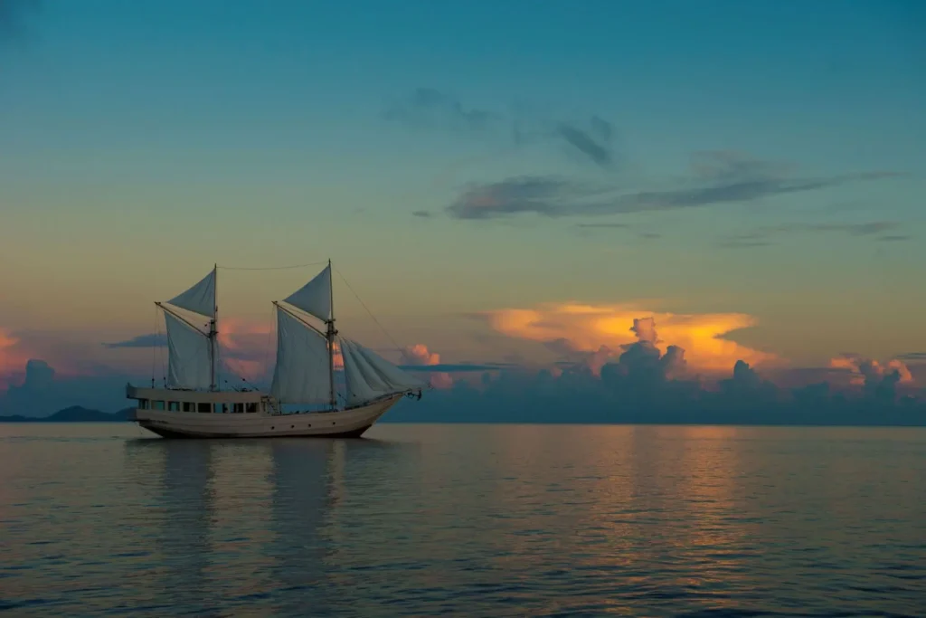 Alexa phinisi sailing across calm water at sunset