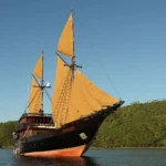 Alila Purnama phinisi sailing past green Indonesian islands