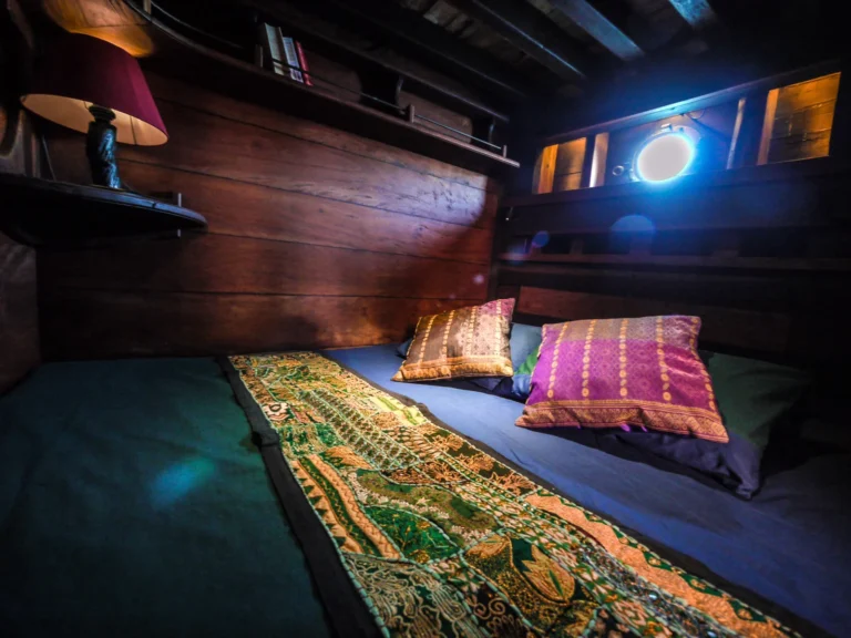 Double cabin with green bed and porthole aboard Ananda
