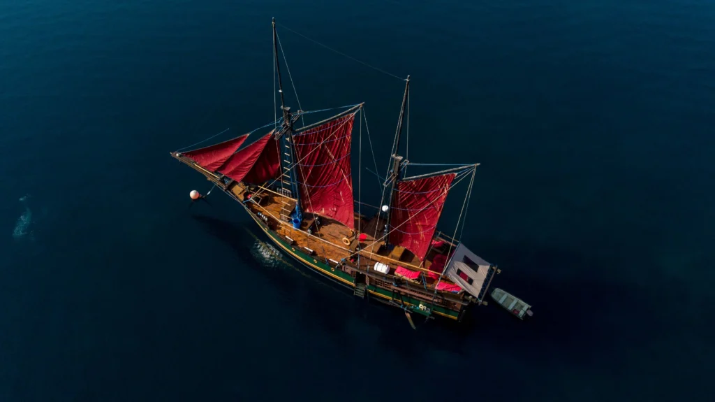 Aerial view of Ananda phinisi under red sails