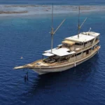 Aerial view of the Athira phinisi cruising deep blue water near Komodo