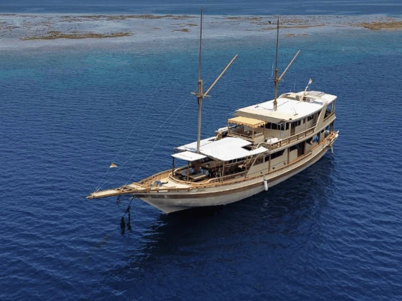 Aerial view of the Athira phinisi cruising deep blue water near Komodo