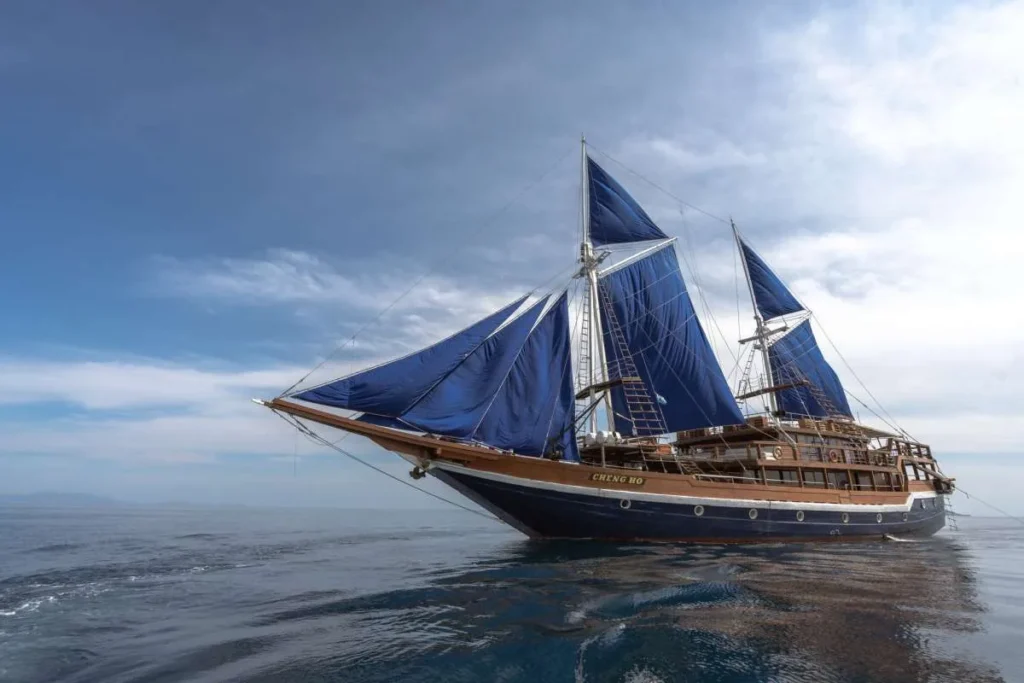 Cheng Ho phinisi sailing on a calm sea with dark blue sails raised