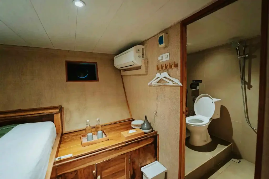 Guest cabin aboard Cordelia with single bed, wooden vanity and an ensuite toilet with shower