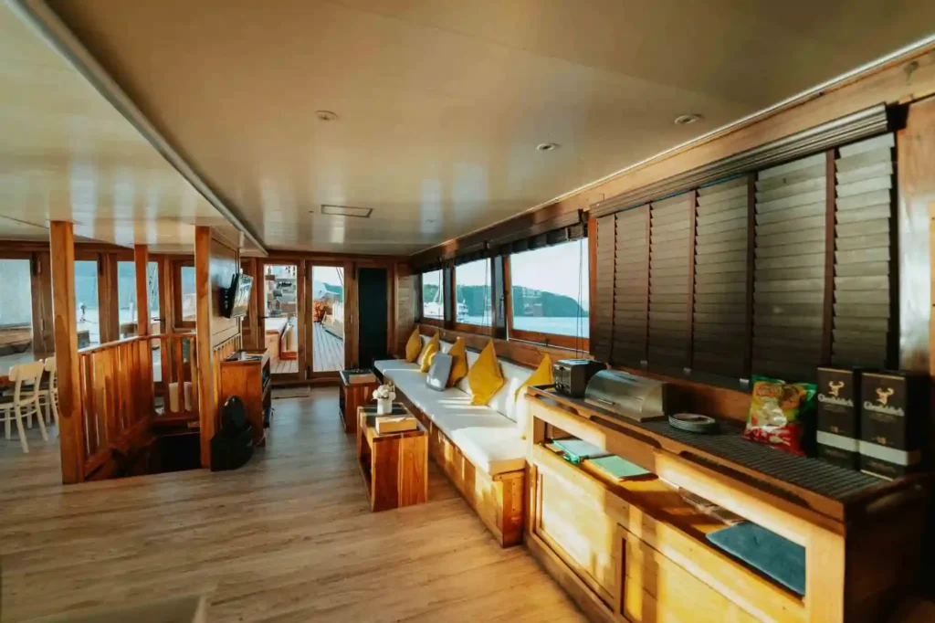 Wood-panelled indoor lounge aboard Cordelia with cushioned bench seating and shuttered windows