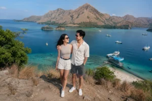 A couple enjoying a breathtaking panoramic ocean view from a hilltop during their exclusive Komodo private charter trip