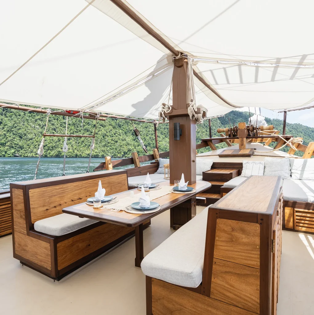 Foredeck dining table and sunbeds aboard Dewata