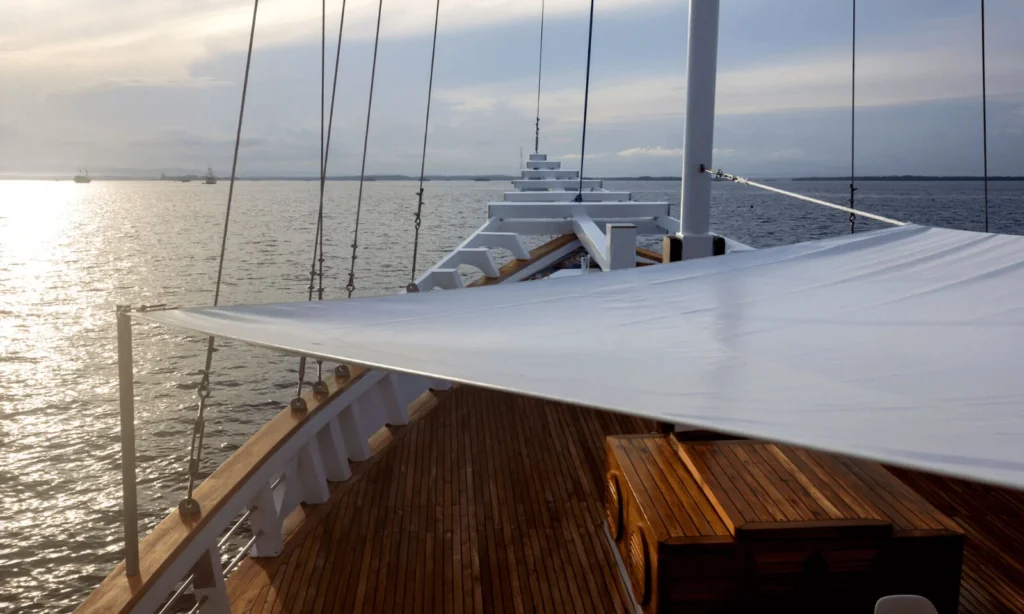 Upper sundeck with lounge beds and panoramic ocean views aboard Fenides