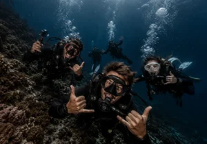 A group of enthusiastic scuba divers taking an underwater photo together over a healthy reef during a Komodo diving expedition.