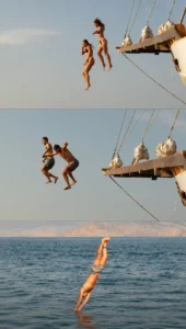 Group of friends having fun jumping off a wooden phinisi boat into the ocean on a Lombok to Komodo cruise.
