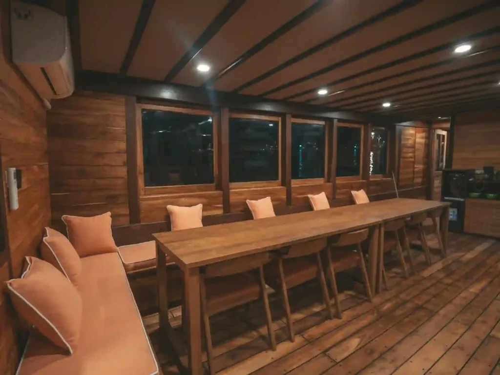 Kanthaka indoor saloon with a long wooden dining table, chairs and cushioned bench seating