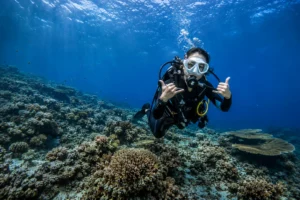 A scuba diver showing a shaka hand sign while exploring the vibrant coral reefs in the clear blue waters of Komodo.