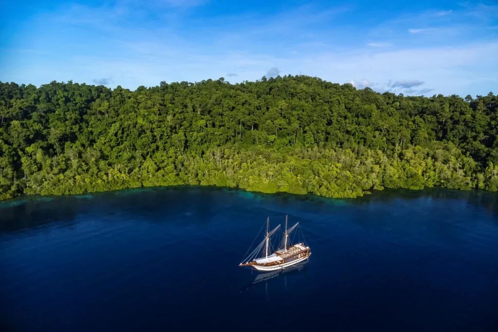 Majik anchored beside a forested Indonesian island