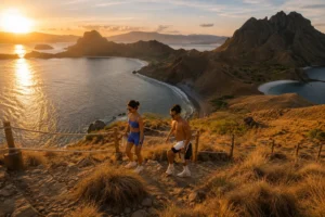 Couple enjoying the panoramic sunrise view at Padar Island viewpoint, a major highlight of the Lombok to Komodo boat trip.