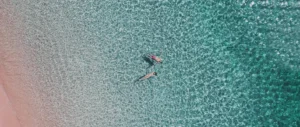 Aerial drone view of crystal clear turquoise water meeting the unique pink sands, a must-visit stop on a Komodo one day tour