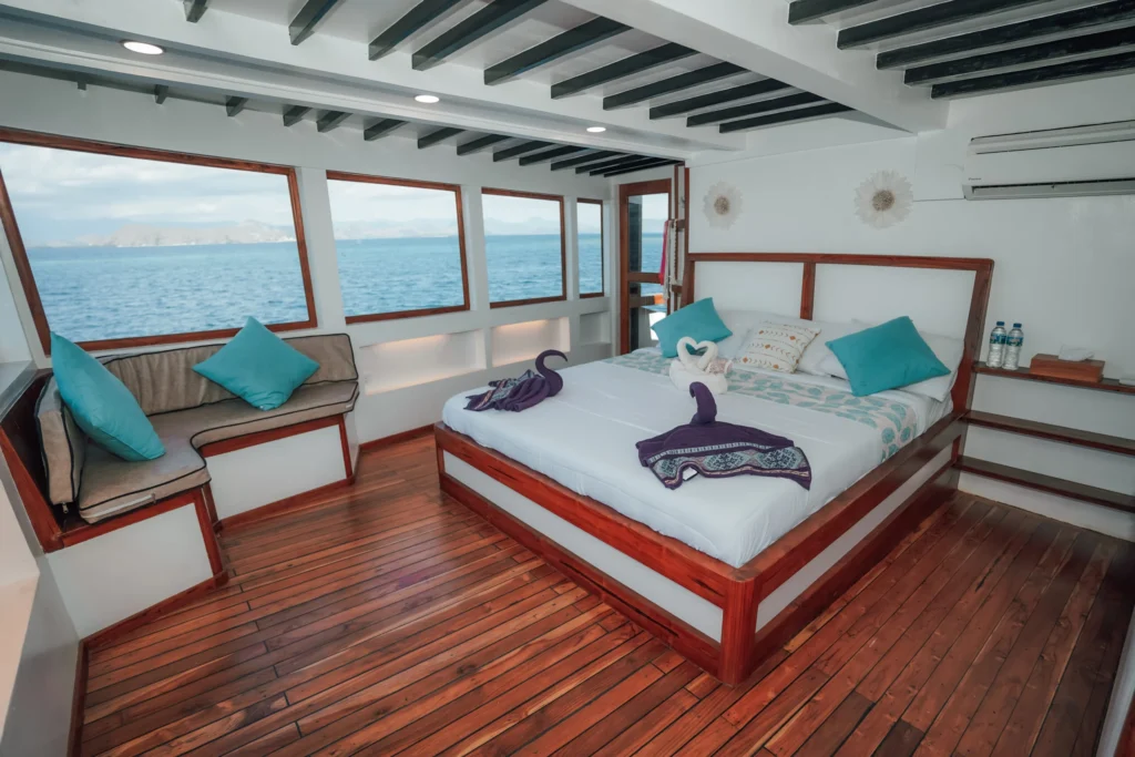 Master cabin with sea-facing windows and a double bed aboard Queenesia II