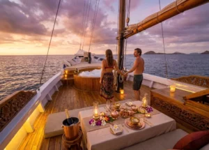 Couple enjoying a romantic sunset dinner on the outdoor deck of a luxury boat sailing to Komodo from Lombok.