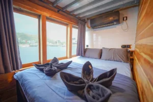 Deluxe cabin aboard Yukai phinisi with queen bed and ocean-view windows