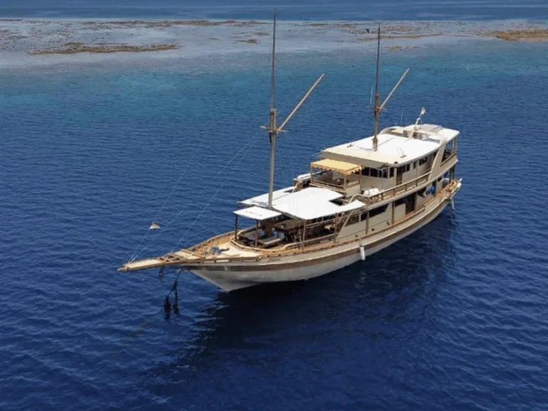 Aerial view of the Athira phinisi cruising deep blue water near Komodo