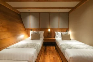 Parallel twin beds with a bedside table in a Celestia Deluxe Suite