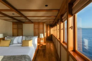 Bed beside panoramic sea view windows in the Celestia Owner’s Suite