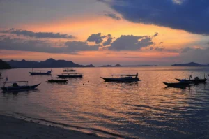 Orange sunset over Labuan Bajo bay with small fishing boats at anchor