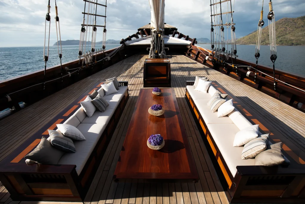 Foredeck lounge with a long table and white sofas aboard Dunia Baru