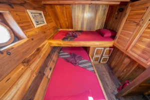 Twin cabin with two single beds and a porthole aboard Kira Kira