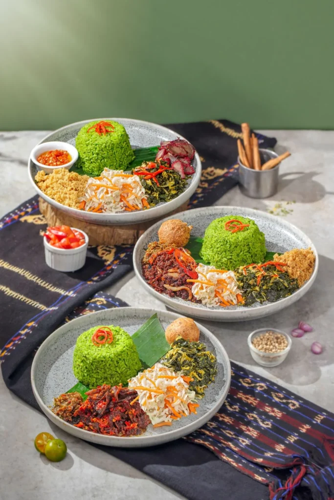 Three plates of yellow rice with sambal and side dishes served at La Moringa