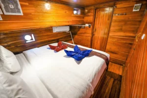 Double bed against timber paneling in a Lady Denok cabin