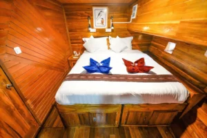Double bed with colorful folded towels in a Lady Denok cabin