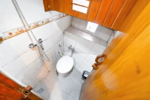 White tiled single cabin bathroom with toilet and shower aboard Lady Denok