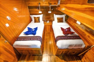 Two single beds with folded towels in a Lady Denok twin cabin