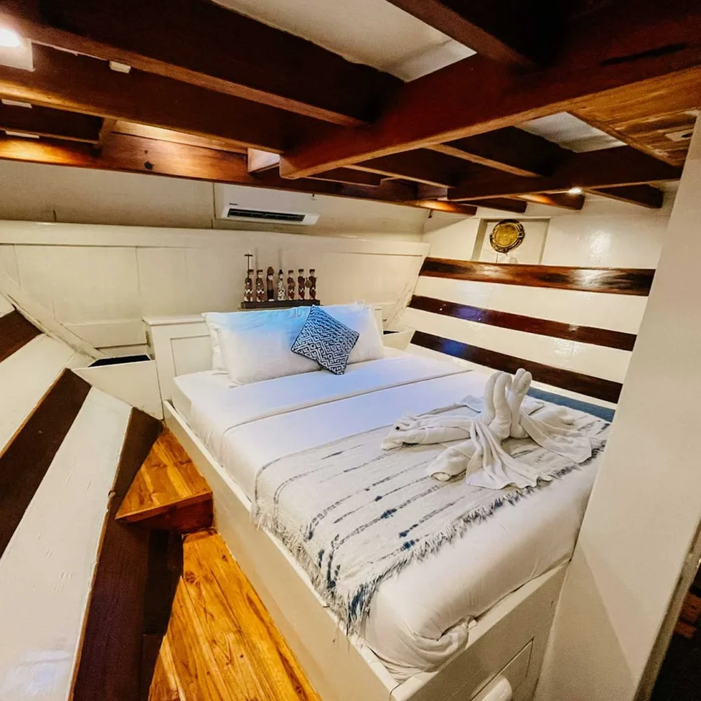 Double bed with towel swans in the white-panelled lower deck cabin of Lambo