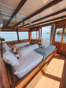 Bed with red cushions beside an island-view window in the Manta Room