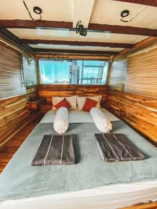 Bed with red bolsters and folded towels in the Turtle Room on Papiton Duwa