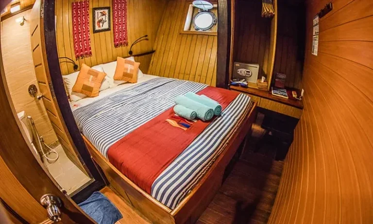 Double bed with towels and red runner in a lower deck cabin of Sea Safari eight
